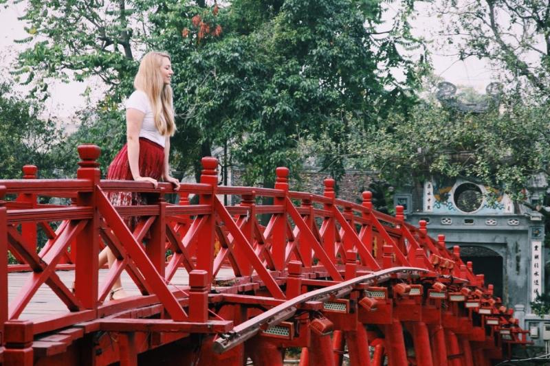 Hình ảnh cây kem Tràng Tiền nổi tiếng trên tay, phía sau là cảnh Hồ Gươm và người đi dạo, thể hiện trải nghiệm ẩm thực kết hợp ngắm cảnh